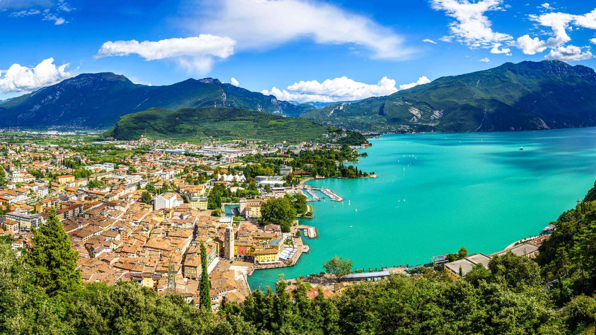 Blick über die Dächer von Riva del Garda auf das türkisfarbene Nordufer des Gardasees und die Berge
