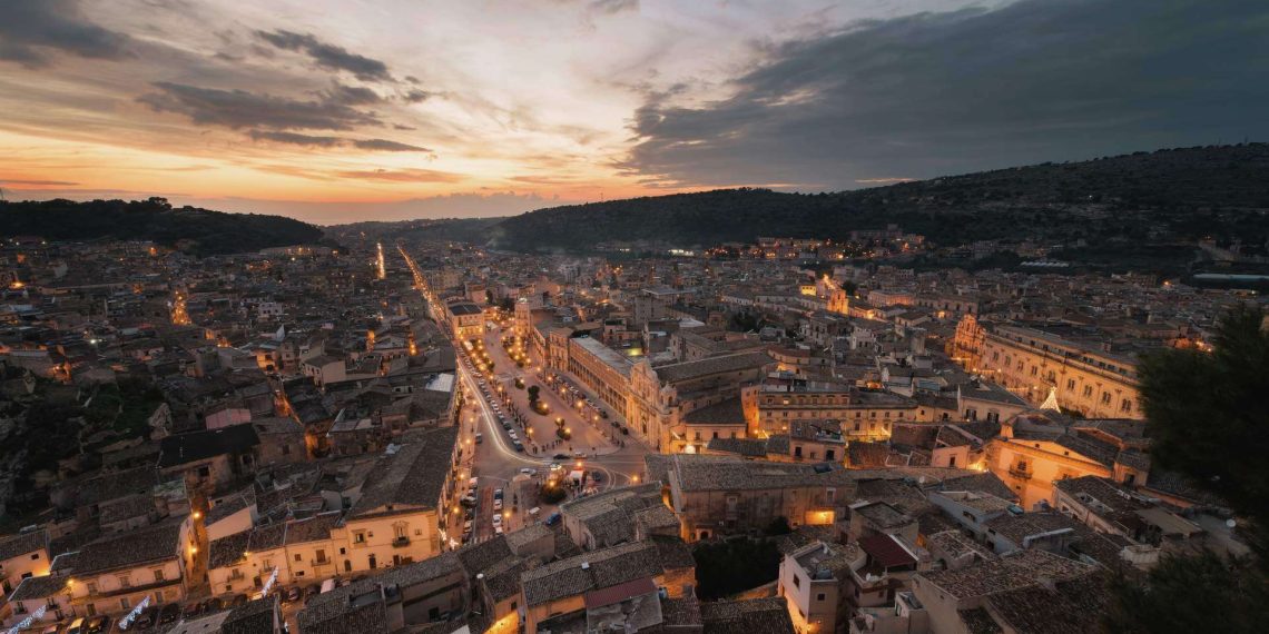 Beleuchtete Altstadt von Scicli im Tal unter einem Abendhimmel
