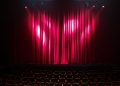 Leere Theaterbühne mit roten Vorhängen und roten Sitzreihen im Zuschauerraum