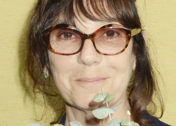 Porträt von Sophie Calle mit dunklem Haar, großer Brille und Blumen beim FILAF in Perpignan 2015