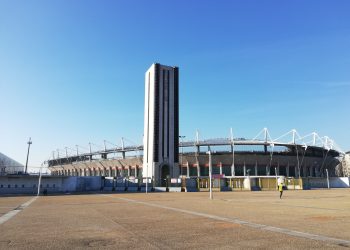 Außenansicht des Stadio Olimpico Grande Torino mit seinem hohen Turm und dem Vorplatz bei blauem Himmel