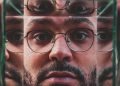 Das Gesicht eines Mannes mit schwarzer Brille spiegelt sich mehrfach in Spiegelflächen